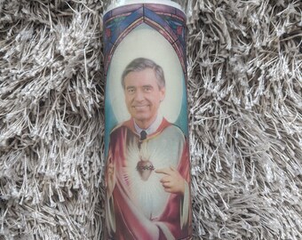 May include: A white candle with a colorful image of a man with a heart on his chest. The image is surrounded by a stained glass border.