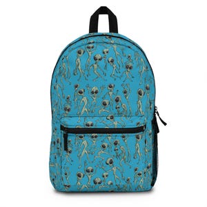 May include: A blue backpack featuring a repeating pattern of cartoon aliens in various poses. The aliens are light green with large black eyes. The backpack has a black top handle, black zippers, and a black mesh side pocket.