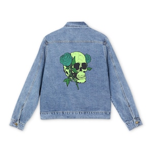 May include: Pale blue denim jacket featuring a neon green skull and teal roses graphic on the back. The jacket has a classic design with buttoned cuffs and a button-down front.