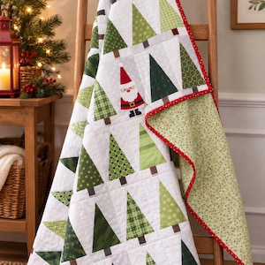 May include: A quilted blanket featuring a repeating pattern of various green Christmas trees on a white background, interspersed with a small Santa Claus figure. The quilt has a red border with white dots and a light green backing with small dots.