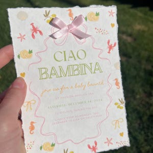 May include: A pink and white baby shower invitation with a green and white title that says "Ciao Bambina". The invitation is decorated with illustrations of lemons, seahorses, and starfish. The text on the invitation reads "Join us for a baby brunch at Pavilion Mooloolaba, Saturday, December 14, 2024, 12 o'clock, during the day. Kindly RSVP by Monday, 2nd December to Lisa on 0413718535."