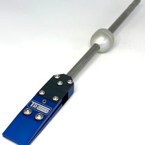 Peut inclure: Un outil en métal bleu et noir avec une tige argentée et une boule blanche à l'extrémité. L'outil porte l'inscription "TR MAKER".