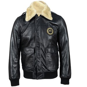 Könnte beinhalten: Schwarze Lederjacke mit beigem Kunstfellkragen. Die Jacke hat zwei Vordertaschen, einen gerippten Saum und Bündchen sowie einen runden Aufnäher auf der Brust. Die Jacke hat einen klassischen Fliegerstil.
