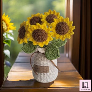 May include: A handcrafted crochet bouquet of sunflowers in a white vase. The sunflowers have yellow petals and brown centers, with green leaves. The vase has a small leather tag that says "keep your smile".