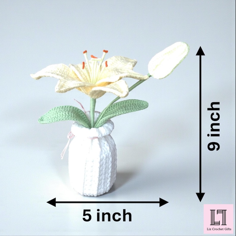 May include: A crocheted cream-colored lily flower with orange stamens and green leaves in a white crocheted vase. The item measures 9 inches in height and 5 inches in width as indicated by the text and arrows. The logo Liz Crochet Gifts is visible.