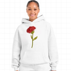 May include: White hoodie with a red carnation flower graphic. The flower is detailed with green stem and leaves. The hoodie has a front pocket and a hood. The overall design is simple and clean, suitable for casual wear.