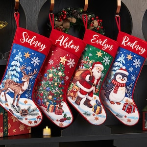Peut inclure: Quatre chaussettes de Noël personnalisées suspendues en rangée. La première est bleue avec un cerf, la deuxième rouge avec un sapin, la troisième verte avec le Père Noël et la quatrième bleue avec un pingouin. Chaque revers blanc porte un nom.