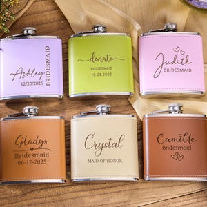 Puede incluir: Seis petacas personalizadas en varios colores, incluyendo lavanda, verde y rosa. Cada petaca está grabada con un nombre y la palabra "Dama de honor" o "Dama de honor", junto con una fecha. Las petacas tienen una tapa plateada y un exterior similar al cuero.