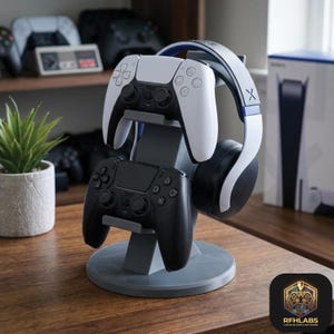 May include: A gray plastic gaming accessory stand featuring a circular base and two tiers. The top tier holds a white and black wireless controller, while the bottom tier holds a solid black wireless controller. A white and black headset rests on the side.