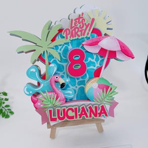 May include: A multi-layered paper cake topper featuring a pink flamingo, a beach ball, a palm tree, and a pink umbrella. The design includes the number 8, the text "Let's PARTY!", and a banner with the name "LUCIANA" in red letters on a light pink background.