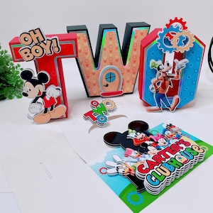 K&ouml;nnte beinhalten: Ein farbenfrohes Geburtstagsdekorationsset mit den Buchstaben "TWO" und einem "Carter's Clubhouse"-Schild. Das "T" ist rot mit dem Text "OH BOY!" und einer Mickey Mouse-Grafik. Das "W" ist schwarz mit einem T&uuml;rdesign. Das Set enth&auml;lt Goofy.