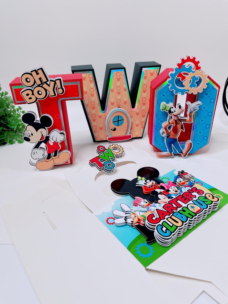 K&ouml;nnte beinhalten: Ein farbenfrohes Geburtstagsdekorationsset mit den Buchstaben "TWO" und einem "Carter's Clubhouse"-Schild. Das "T" ist rot mit dem Text "OH BOY!" und einer Mickey Mouse-Grafik. Das "W" ist schwarz mit einem T&uuml;rdesign. Das Set enth&auml;lt Goofy.
