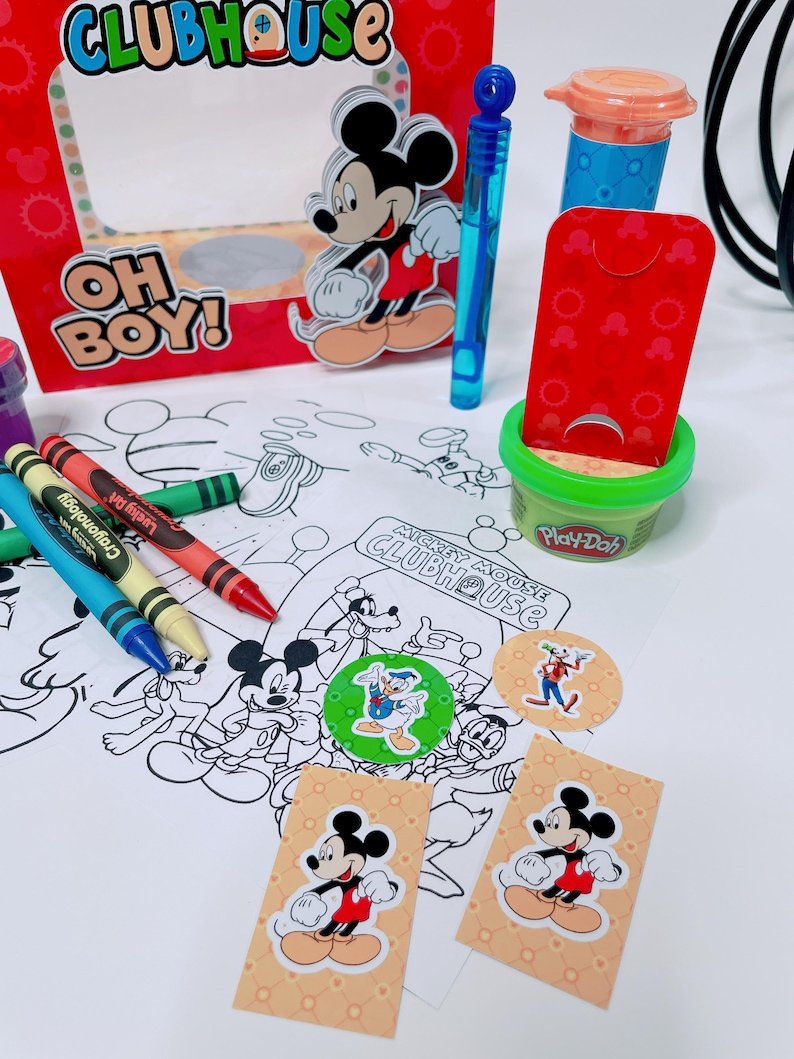 May include: A colorful Mickey Mouse Clubhouse-themed party set. Includes a red box with Mickey, crayons, Play-Doh, stickers, and a coloring sheet. The box reads "OH BOY!" and "CLUBHOUSE".