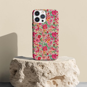 Puede incluir: Una funda de teléfono floral con un patrón floral rosa, rojo y verde. La funda está diseñada para un iPhone.