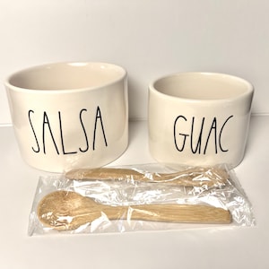 May include: Off-white ceramic salsa and guacamole bowls with black lettering. Two small wooden spoons are packaged in clear plastic. The salsa bowl is larger than the guacamole bowl.