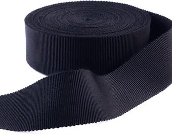 May include: A roll of black grosgrain ribbon. The ribbon is folded in half and the roll is visible in the background.