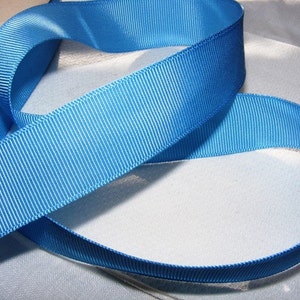 May include: A roll of bright blue satin ribbon with a ribbed texture.