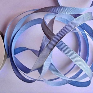 Könnte beinhalten: Nahaufnahme eines blauen und violetten Ombre-Bandes. Das Band ist aus einem weichen, seidenartigen Material gefertigt und hat einen dezenten Glanz.