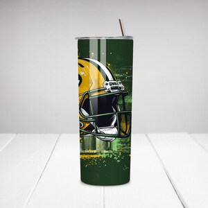 May include: A green and yellow tumbler featuring a football helmet design. The helmet is yellow and green, with a black facemask. The background has a green and yellow cityscape design. A straw is inserted in the lid.