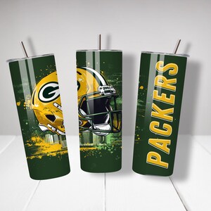May include: Three green and yellow insulated tumblers with the Green Bay Packers logo and helmet design. Each tumbler has a silver lid and a straw. The Packers logo and helmet are in yellow and green.
