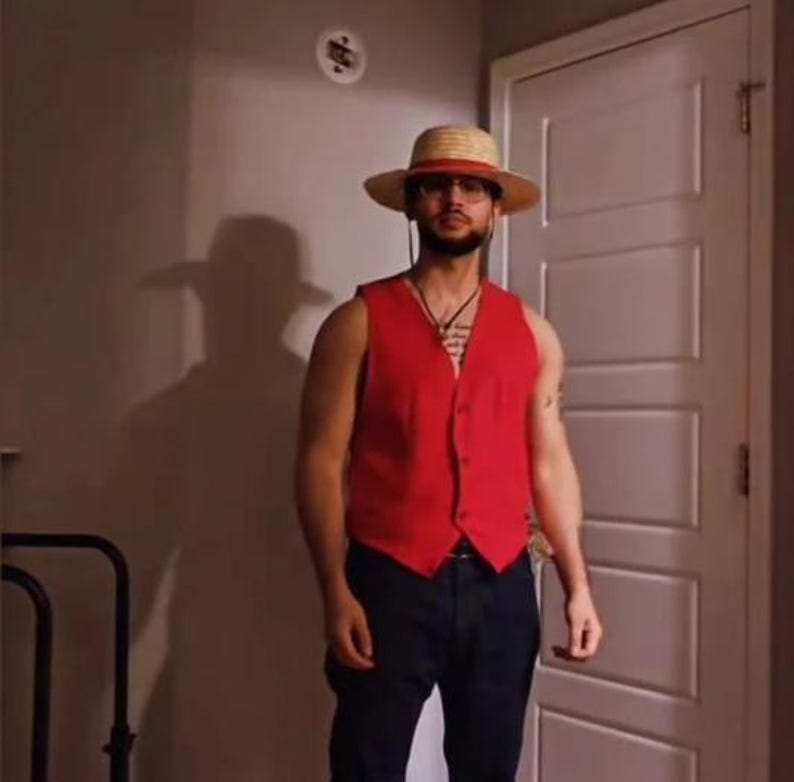 K&ouml;nnte beinhalten: Ein Strohhut mit breiter Krempe und rotem Band, kombiniert mit einer roten Weste und dunkelblauen Hosen. Die Weste hat ein Knopfdesign. Das Outfit erinnert an eine Figur aus einer beliebten Anime-Serie.