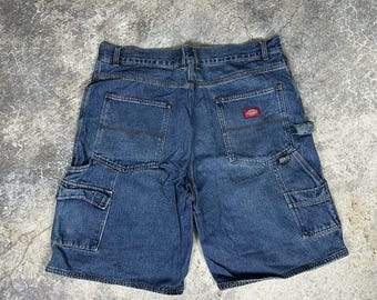 May include: Blue denim shorts with multiple pockets, including cargo pockets on the sides. The shorts have a classic design with a red logo patch on the back pocket. The shorts are made of durable denim material.