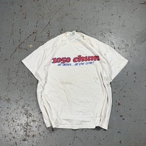 May include: A white t-shirt featuring the text "1050 chum all oldies...all the time!" in red and blue. The shirt is creased and has a vintage appearance.