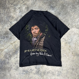 May include: Black t-shirt featuring a portrait of Jimi Hendrix. The image includes the text "Jimi Hendrix" above the phrase "Hear My Train A Comin'". The shirt is made of a soft material and has a crew neck.