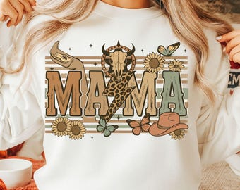 May include: White sweatshirt with a brown, white, and green graphic design that says "MAMA" with a skull, lightning bolt, butterflies, and sunflowers.
