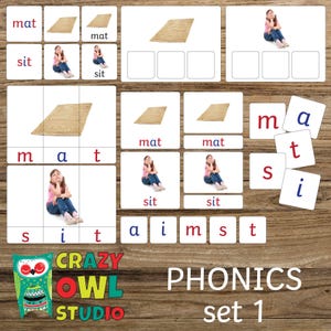 Op de afbeelding: Educatieve set voor fonetiek met woord- en beeldkaarten. De kaarten tonen woorden als "mat" en "sit", samen met afbeeldingen van een mat en een meisje. De set bevat lettertegels en is gelabeld "PHONICS set 1".
