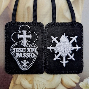 May include: Two black scapulars with white embroidered designs. One features a cross and heart with the text "JESU XPI PASSIO". The other has a heart with swords. Each has a black cord for wearing.
