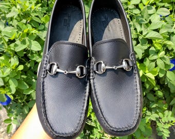 May include: A pair of black leather loafers with silver horse bit accents. The loafers have a pointed toe and a slip-on design.