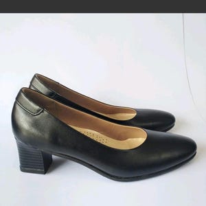 以下が含まれることがあります： 低いブロックヒールが付いた黒の革製のヒールパンプス2足