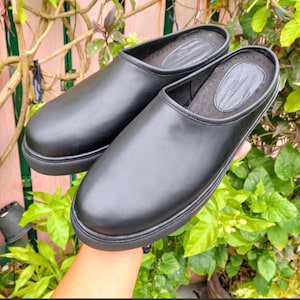 May include: Pair of black leather slip-on shoes with a rounded toe and a flat sole.