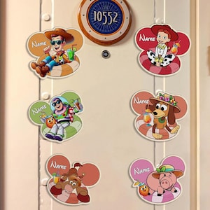 May include: A white door adorned with colourful Disney character magnets. The magnets feature characters such as Woody, Buzz Lightyear, and Jessie, each with a name tag. A circular sign with the number "10552" is above the magnets.