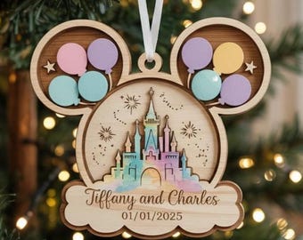 May include: A wooden ornament shaped like a mouse head featuring a central castle illustration with pastel colors, surrounded by small balloon cutouts in pink, purple, and blue. The text Tiffany and Charles 01/01/2025 is engraved below.