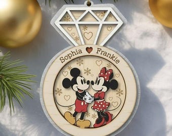 May include: A wooden ring-shaped Christmas ornament featuring a diamond-cut top and a central circular design. The ornament displays the names Sophia and Frankie with a graphic of Mickey and Minnie Mouse surrounded by small hearts and snowflakes.
