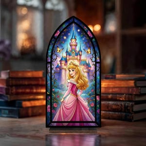May include: A stained glass panel featuring a princess in a pink gown standing in front of a castle. The panel has a black frame and is set on a wooden base. The background shows a castle, butterflies, and flowers.