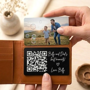 May include: A brown leather wallet holds two personalized cards. One card features a photo of a man and child blowing bubbles. The other card is black with a QR code and the text "Billy and Dad's best moments" and "Love, Billy."