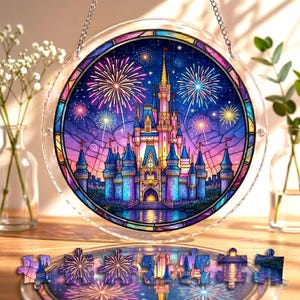 May include: A round stained glass puzzle featuring a castle with fireworks against a night sky. The puzzle is in a clear, circular frame, hanging from a chain. Several puzzle pieces are scattered below.