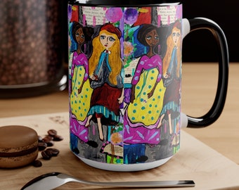 May include: A white ceramic mug with a black handle features a colorful illustration of three women in dresses with polka dots. The background is a collage of colorful patterns and text.
