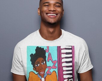 May include: A white t-shirt with a graphic print of a cartoon person playing a keyboard. The graphic is in a colorful style with blue, orange, yellow, and pink colors. The text "JAZZ" is written in large letters on the graphic.