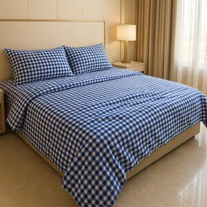 Pode incluir: Uma cama com um conjunto de lençóis com padrão xadrez azul e branco. Duas fronhas a condizer são visíveis. A cama está num quarto bem iluminado com uma paleta de cores neutras.