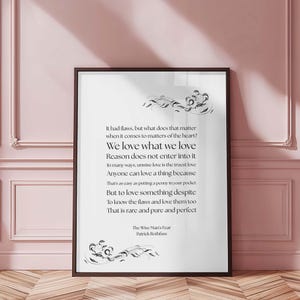 Op de afbeelding: Een ingelijste print met zwarte tekst op een witte achtergrond. De tekst is een gedicht met de titel "We love what we love". Decoratieve bloemelementen zijn boven en onder. De lijst is donkerbruin. Van Patrick Rothfuss.