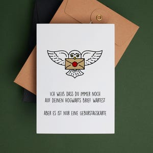 May include: A white card with a black and white illustration of an owl carrying a letter with a red wax seal. The text on the card reads "ICH WEIB DASS DU IMMER NOCH AUF DEINEN HOGWARTS BRIEF WARTEST ABER ES IST NUR EINE GEBURSTAGSKARTE".