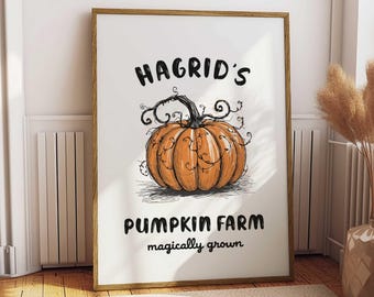 May include: A framed art print featuring a hand-drawn orange pumpkin with the text "Hagrid's Pumpkin Farm" and "magically grown" in black lettering. The artwork is set against a white background, framed in a wooden frame.
