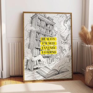 May include: A framed black and white illustration of a bookshelf, open book, and dragons. The text "REALITY PAUSED FANTASY LOADING" is in yellow. The artwork is in a wooden frame and is displayed in a room with a rug and vase.