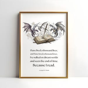 Pode incluir: Impressão artística emoldurada com borda dourada. A ilustração de fantasia apresenta dragões, uma espada e um livro aberto. O texto diz: "Eu vivi mil vidas... Porque eu leio." de George R. R. Martin.