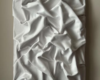 Könnte beinhalten: Ein rechteckiges Kunstwerk aus weißem Stoff mit einem drapierten, strukturierten Aussehen. Der Stoff ist straff gespannt und gefaltet, wodurch ein dynamisches Zusammenspiel von Schatten und Lichtern entsteht. Das Kunstwerk ist an einer Wand in neutralen Tönen befestigt.