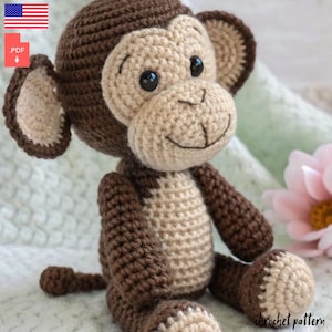 Può includere: Schema all'uncinetto per un giocattolo amigurumi di scimmia marrone e beige. La scimmia ha un viso sorridente con occhi neri e un naso marrone. Lo schema è disponibile per il download in PDF.